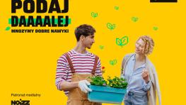 Mężczyzna w ogrodniczkach trzyma skrzynkę z roślinami i patrzy na stojącą obok kobietę, napis "Podaj dalej".